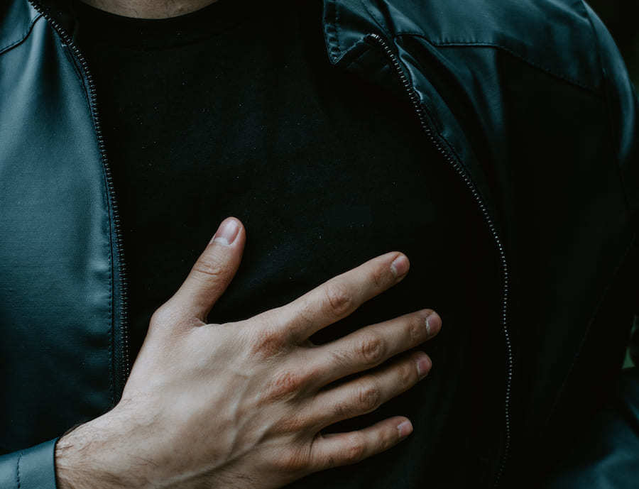 man hand on chest cause of acking heart