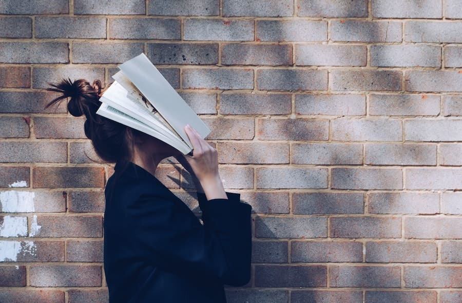 woman covers head with book
